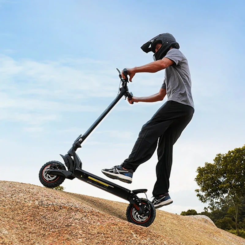 Une personne portant un casque de protection intégral effectue une manœuvre sur une trottinette électrique tout-terrain sur un monticule rocheux.